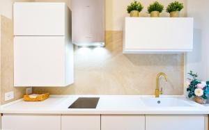 a kitchen with white cabinets and a sink at Lecco Antico Pozzo - Modern Suite in Lecco
