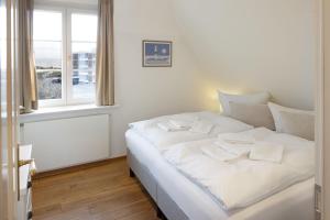 un lit blanc dans une chambre avec une fenêtre dans l'établissement Senenskiin, à List auf Sylt