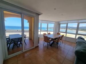 a dining room with a table and chairs and the ocean at Dúplex 4 dormitorios en Playa Rapadoira in Foz