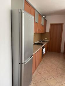 a stainless steel refrigerator in a kitchen with wooden cabinets at Appartamento Luce in Durrës