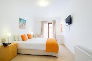 a white bedroom with a bed and a television at Enosis Apartments - Kalypso Beach Flat in Agia Anna Naxos