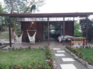 a house with a patio with a table and hammocks at Cabaña Tesoro Escondido in Guápiles