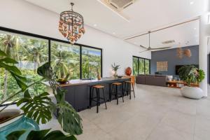 an open kitchen and living room with a bar with stools at Villa Bond Seaview Villa in Chaweng Noi Beach