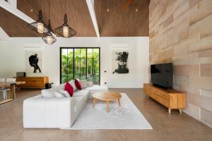 a living room with a white couch and a tv at Villa Mangosteen spacious 3br Pool villa in Ban Thung