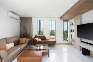 a living room with a couch and a tv at Villa Lom Talay - Family Retreat in Ban Thong Phlu