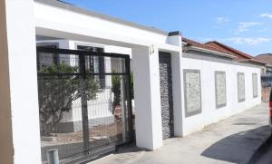 a white building with a gate in front of it at Optimum Stay Self Catering Accommodation - Deluxe Room in Cape Town