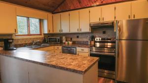 una cucina con elettrodomestici in acciaio inossidabile e mobili in legno di Lookout Lodge - Hot tub, Views, Xbox, Bar a Beech Mountain