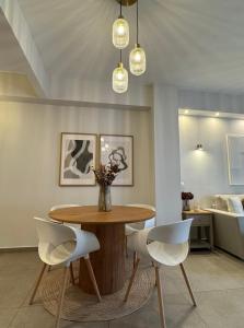 a dining room with a wooden table and white chairs at Acropoli 1 Bedroom Flat with Rooftop Acropolis View in Athens +4 photos