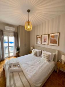a bedroom with a large white bed with a chandelier at Acropoli 1 Bedroom Flat with Rooftop Acropolis View in Athens