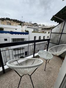 two chairs and a table on a balcony with buildings at Acropoli 1 Bedroom Flat with Rooftop Acropolis View in Athens
