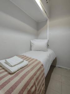 a white bedroom with a bed with a striped blanket at Kolonaki 2 bedroom Flat in Athens +16 photos