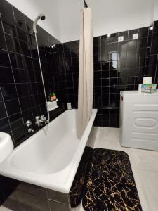 a black tiled bathroom with a tub and a shower at Kolonaki 2 bedroom Flat in Athens