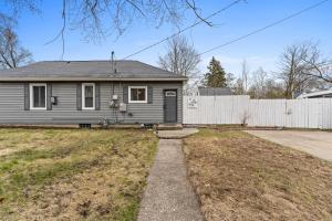 a gray house with a fence in a yard at Cozy Vacation Rental- Short distance to Lake Mi in Muskegon