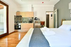 a bedroom with a large white bed and a kitchen at City Center Flat with Terrace (Capparis) in Athens