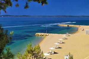 a beach with chairs and umbrellas in the water at Split Apartments Shell in Split
