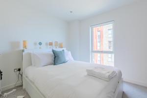 a white bed with white pillows and a window at Gorgeous 1Bd Flat with incredible views of the O2 in London