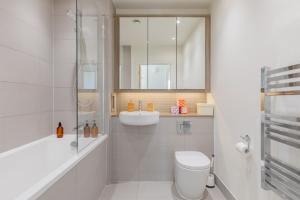 a white bathroom with a toilet and a sink at Gorgeous 1Bd Flat with incredible views of the O2 in London