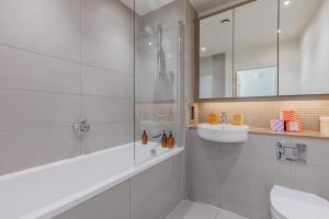 a white bathroom with a shower and a sink at Gorgeous 1Bd Flat with incredible views of the O2 in London +15 photos