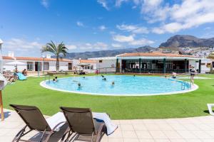 ein großer Pool mit Stühlen und Menschen darin in der Unterkunft Modern studio with ocean views and heated pool in Malibu Park in Adeje
