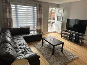 a living room with a leather couch and a coffee table at Luxieux Appartement laval in Laval