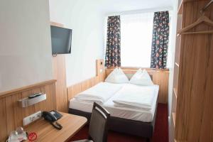 a hotel room with a bed and a desk with a phone at Pension Dr. Geissler in Vienna +20 photos