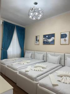 a room with four beds with blue curtains and a chandelier at UMMU ROHAT guest house in Samarkand