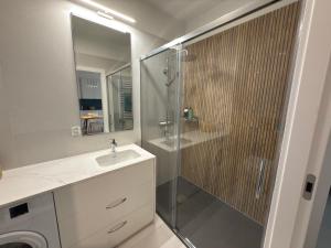 une salle de bain avec une douche et un lavabo et une cabine de douche en verre dans l'établissement Baltic SEA apartament z dostępem do basenu,sauny ,jacuzzi i hali sportowej, à Gąski 6 autres photos