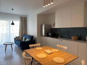 une cuisine et une salle à manger avec une table et des chaises en bois dans l'établissement Baltic SEA apartament z dostępem do basenu,sauny ,jacuzzi i hali sportowej, à Gąski