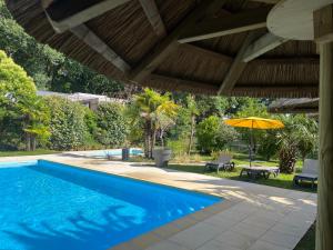a swimming pool with an umbrella and a patio at Camping JOBEL in Tarnos