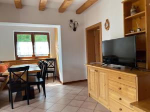 a living room with a television and a table with chairs at Appartamento Candido Dolomiti CEDANOSTRA in Candide