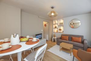 a living room with a table and a couch at Le Calain, Élégance et Confort à 50 m de la Plage in Wimereux