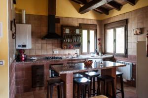 a kitchen with a large counter with stools in it at Ramajal Rural in Horcajo