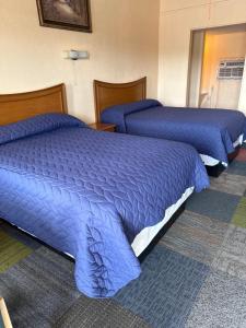 two beds in a hotel room with blue blankets at Relax Inn Goldthwaite in Goldthwaite +4 photos