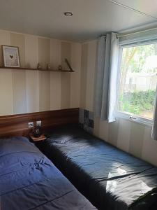 two beds in a room with a window at Mobil Home climatisé 3 chambres - Parc des 7 fonts in Agde
