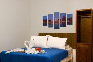 a bedroom with a bed with blue sheets and paintings at Hope Pousada in Arraial do Cabo