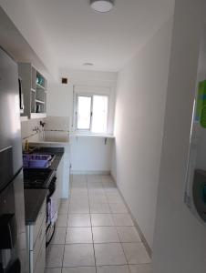 une cuisine blanche avec un évier et une fenêtre dans l'établissement Apart Paraná, à Paraná