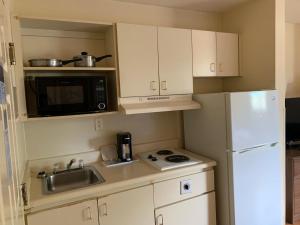 a small kitchen with white cabinets and a white refrigerator at Motel 6 Myrtle Beach in Myrtle Beach