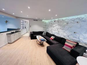 a living room with a black couch and a stone wall at Maison Chez Nous Cap D ail villa à 5 min de Monaco in Cap d'Ail