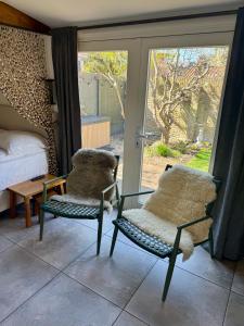Un dormitorio con dos sillas y una cama y puertas corredizas de vidrio. en Wanderlust - Vlakbij strand - Omheinde privétuin, en Noordwijk aan Zee