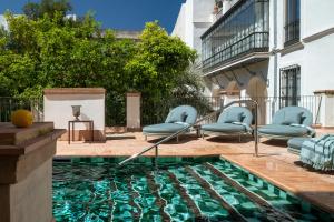 Una piscina con sillas azules en un patio. en Hotel Boutique Casa del Limonero, en Sevilla