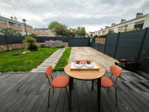 a wooden table and chairs on a patio with a table and chairs at Le Cupidon, cocon privé avec Spa, Sauna, Cinéma Netflix et Jardin privé in Montigny-le-Bretonneux