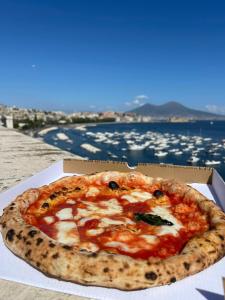 a pizza in a box with a view of the water at Île Déluxe Apartment in Sorrento