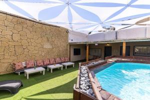 a swimming pool with benches and a stone wall at Fata morgana Hostel in Beer Sheva