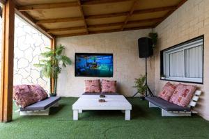 a patio with two couches and a table and a tv at Fata morgana Hostel in Beer Sheva