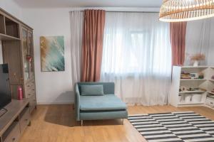 ein Wohnzimmer mit einem blauen Stuhl vor einem Fenster in der Unterkunft Spacious apartment Near National Arena, park in Bukarest