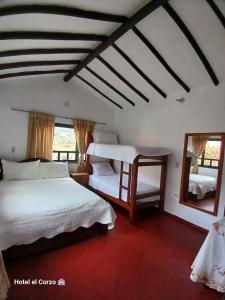 ein Schlafzimmer mit zwei Betten und einem Spiegel in der Unterkunft HOTEL El CORZO DE LA VILLA in Villa de Leyva