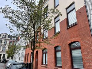 a red brick building with a tree in front of it at Gemütlich & Zentral - Familien-Oase mit Balkon,Waschmaschine, Trockner für 4 Personen in Bremerhaven