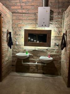 a stone bathroom with two sinks and a fireplace at Vale do Rio Bonito Glamping in Riozinho