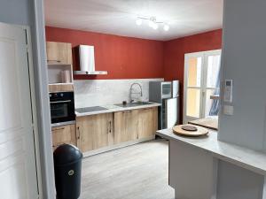 a large kitchen with red walls and wooden cabinets at Maison 3 chambres, Agen centre, climatisé, 6 personnes in Agen +5 photos
