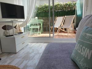 a living room with a television and a patio at Le B - A 200 m de la plage in Arcachon
